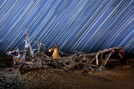 Girl Light Painted on a Ghost Ship With Star Trails on Beachの写真素材