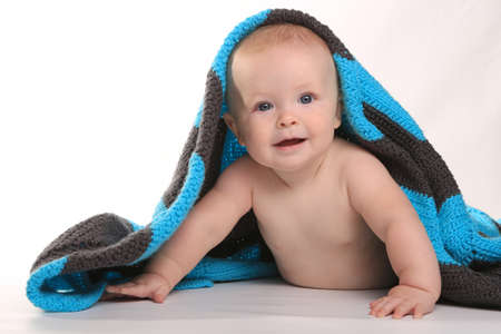 Adorable Baby Smiling Lying on Stomach With Blanket on White Backgroundの写真素材