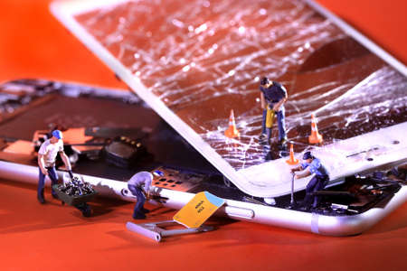 Miniature People Fixing and Repairing a Cracked Broken iPhoneの写真素材