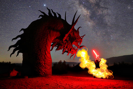 Woman Holding a Sword Against a Fire Breathing Serpent at Nightの写真素材