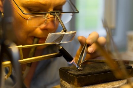 Uppsala, Sweden - June 13, 2013  The Goldsmith working with an earring, solder a new pin with the gas-flame from the soldering-lampのeditorial素材
