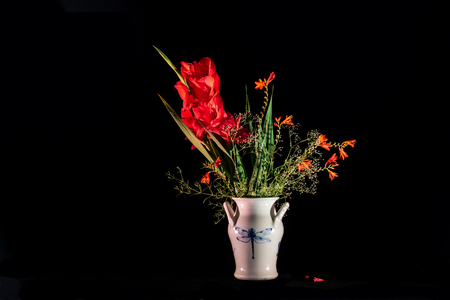 A lovely bouquet in red with gladiolus, montbretia 'Lucifer'  and baby's breath in a dragonfly pottery.の写真素材