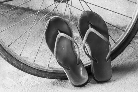 Old slippers and bicycle wheel in black and white toneの写真素材