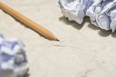 Crumbled paper and pencil on brown wrinkled paperの写真素材