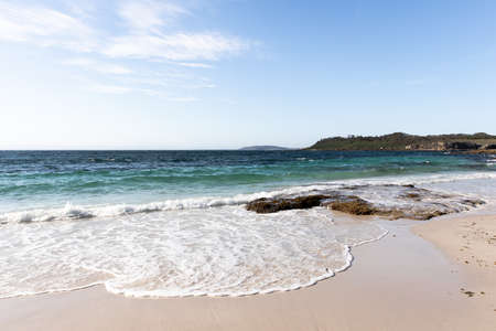 A sunny, beautiful day at the beach with the water reaching the shoreの写真素材