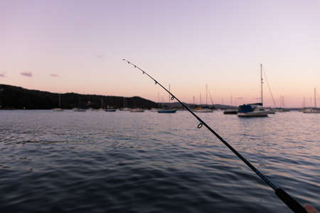 Fishing at sunset with a view of the water and boatsの写真素材