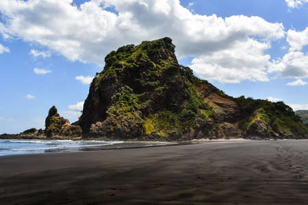Black sandy beach with a tall rock formationの写真素材