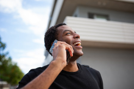 Close-up shot of a man holding a smartphone and smiling while speakingの写真素材
