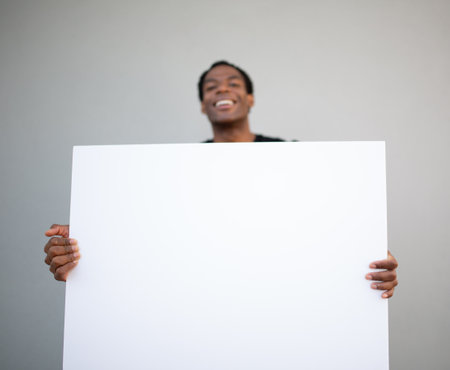 A man presenting a large blank white poster with both handsの写真素材
