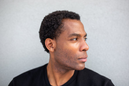 Close-up side profile of a man looking to the right, against a grey wallの写真素材