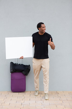 Man in casual attire holding a blank white sign in one hand and giving a thumbs up with the otherの写真素材