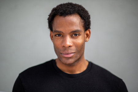 Close-up portrait of a man looking straight into the camera with a serious expression, set against a plain gray backgroundの写真素材