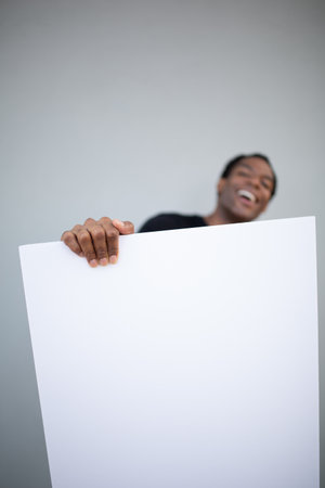 A man laughing and holding a large blank white poster with one handの写真素材