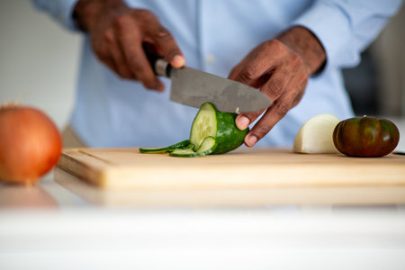 Close-up shot of hands slicing a cucumber on a wooden cutting boardの写真素材