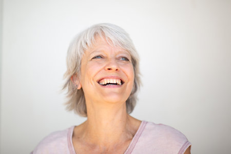 Close-up portrait of a smiling mature woman with short gray hair, looking slightly upward with a joyful expressionの写真素材