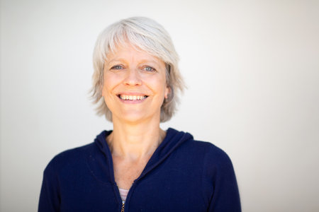 Portrait of a mature woman with short gray hair wearing a navy blue jacket, smiling and looking directly at the cameraの写真素材