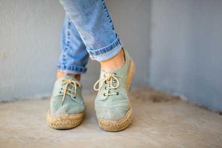 Front view of light green espadrille shoes with woven jute soles, styled with blue jeans rolled at...