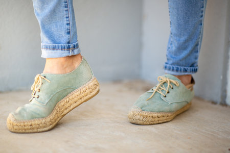 Full view of both feet wearing light green espadrille shoes with jute soles, styled with rolled-up blue jeans, showing a casual and relaxed lookの写真素材