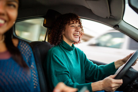 A woman with curly hair, wearing a green sweater, laughs while driving a carの写真素材