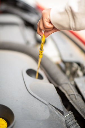 Close-up view of a person's hand pulling out the dipstick to check the oil level in a car engineの写真素材
