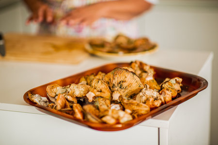 A close-up of a tray filled with fresh wild mushrooms placed on a kitchen counterの写真素材