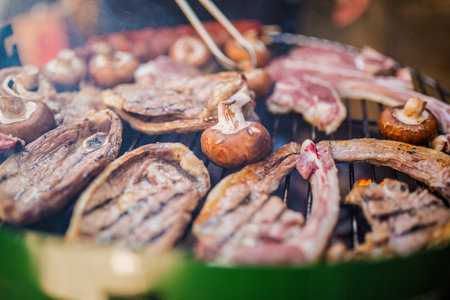 Close-up of meat and mushrooms grilling on a barbecueの写真素材