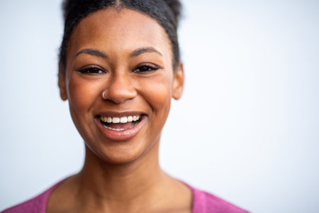 Close-up color portrait of a young woman with a natural afro hairstyle, and a cheerful expression,...