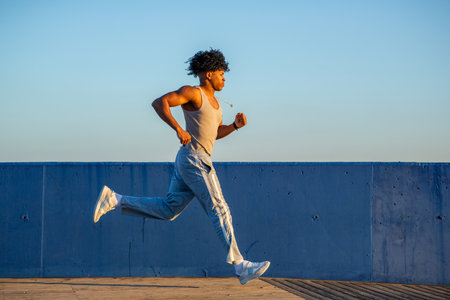 Runner mid-stride on a wooden boardwalk during a fitness session at sunrise, captured in profile with intense focusの写真素材