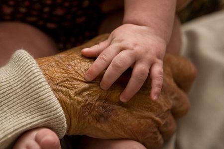 Infant 's hand resting on her greatgrandfather's hand. contrasting the textures of infancy and old...