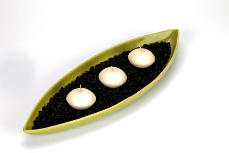 Candle boat with three candles and black pebbles in it.の写真素材