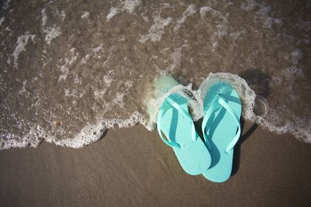 Flip Flop Sandals in the waves of the ocean on the beachの写真素材