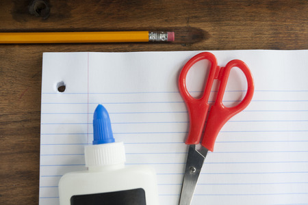 School Notebook Paper, Scissors, Pencil and Glue on Wood Deskの写真素材
