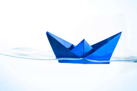 Blue Paper Boat Floating in Water with a White Backgroundの写真素材