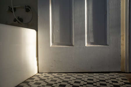 Old Bathroom Door with White Tub and Black and White Tile Flooringの写真素材