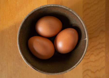 Brown Eggs in a Clay Bowl on a Wood Surfaceの写真素材