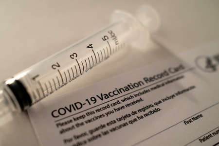 Covid-19 Vaccination Card with a Plastic Syringe on White Backgroundの写真素材