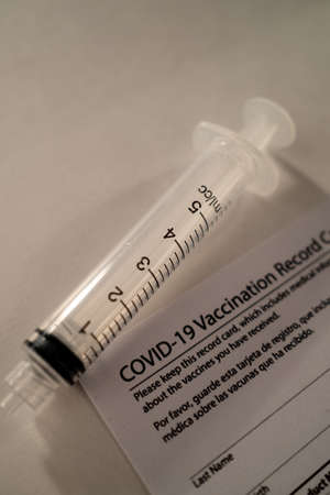 Covid-19 Vaccination Card with a Plastic Syringe on White Backgroundの写真素材
