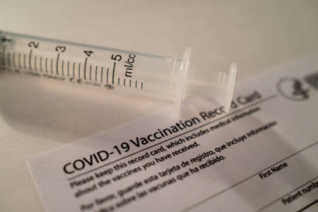 Covid-19 Vaccination Card with a Plastic Syringe on White Backgroundの写真素材