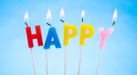 Colorful Birthday Candles on a  Blue Background that Spell Happyの写真素材