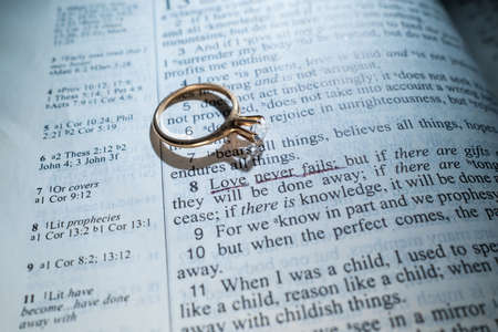 Woman's Gold Wedding Ring on a Bible with the Scripture Love Never Failsの写真素材