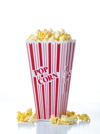 Red and White Striped Popcorn Container with Popcorn on a White Backgroundの写真素材