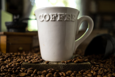 White Mug with the Word Coffee on it in a Pile of Coffee Beansの写真素材