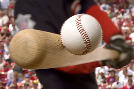 baseball player hits the ball with his bat with crowd in background