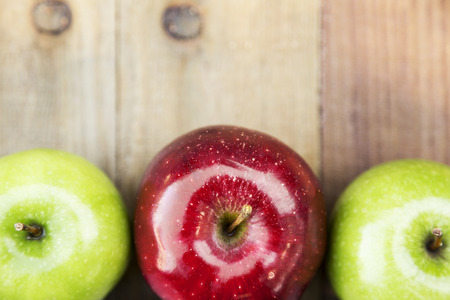 over top view of three farm fresh organic  granny smith and red delicious apples from Michigan on wood planksの写真素材