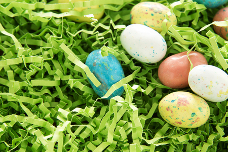 multiple candy eggs resting in green paper grassの写真素材