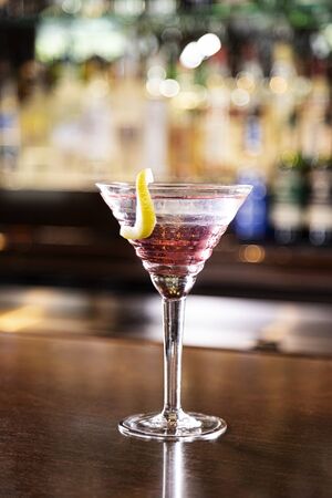 a cosmopolitan in a martini glass on a wood top barの写真素材