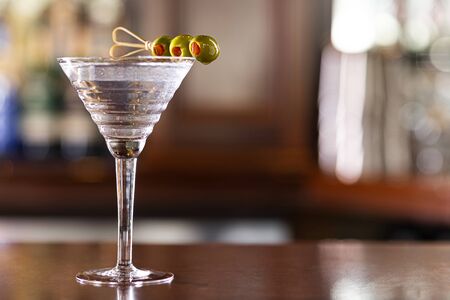 the classic three olive vodka martini sits on a wood bar with copyspaceの写真素材