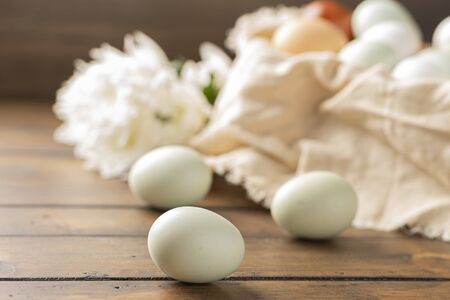 basket of fresh natural organice blue, green, brown and white eggs on wood backgroundの写真素材