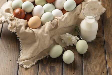 basket of fresh natural organice blue, green
, brown and white eggs on wood background with bottle of milkの写真素材