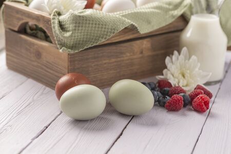 basket of fresh natural organice blue, green, brown and white eggs on wood backgroundの写真素材